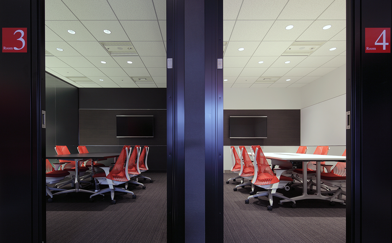 コーポレートカラーの赤、黒、白を貴重とした会議室。壁はホワイトボードとして使用できます。